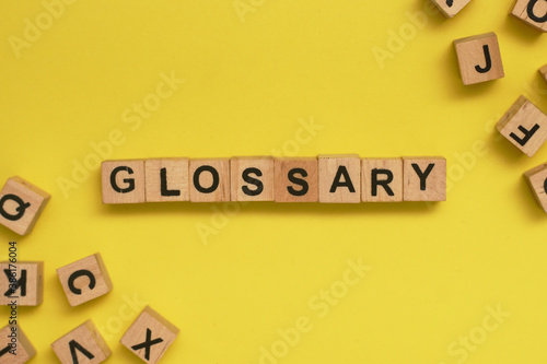 Glossary Word Written In Wooden Cube With Yellow Background