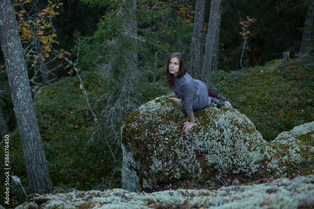 Girl sits on a stone in the forest