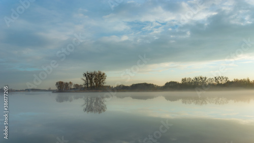 Fog over a calm lake, trees on the horizon