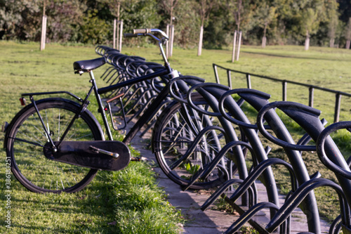 Dark metal Bicycle parking stand or rack  in the park near a lake © ByAmerica