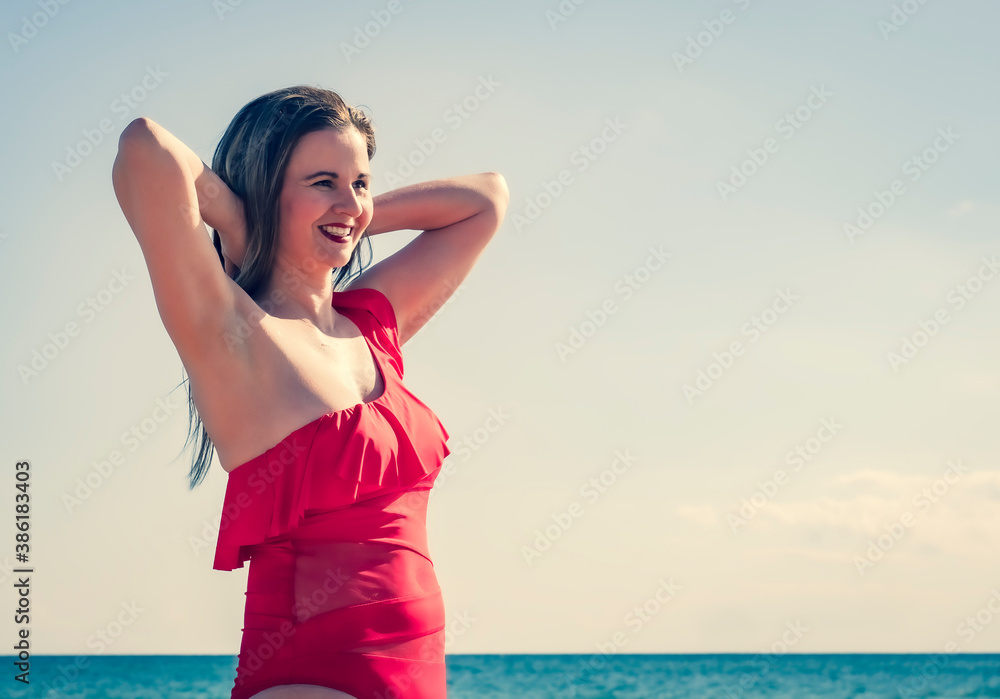 A young slender, beautiful European middle-aged woman flew to rest, mature pants in a red swimsuit against the sky. The wind develops her long dark hair. Copy space A young slender, beautiful European middle-aged woman flew to rest, mature pants in a red swimsuit against the sky. The wind develops her long dark hair. Copy space