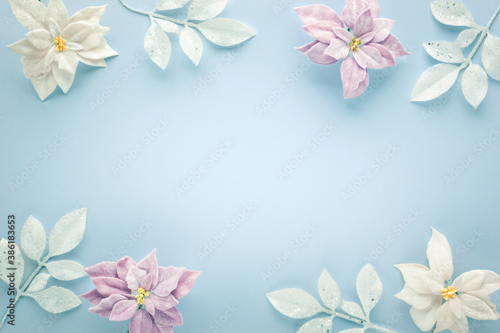 Christmas arrangement with poinsettia flowers and silver leaves on pastel background. Flat lay. Top view, copy space.