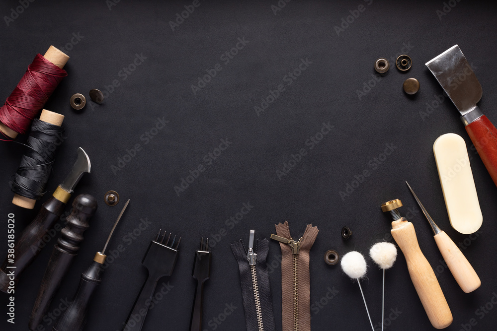set of different tools for making leather goods on black leather background. Manual sewing of the product. place for your text or design. top view set of different tools for making leather goods on black leather background. Manual sewing of the product. place for your text or design. top view