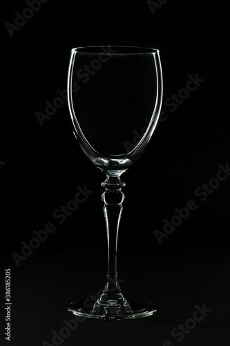 Low key studio image of a wine glass with a black background. The silhouette of the glass is lightning up due to flash light