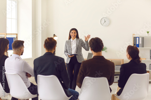 Smiling company manager or team leader greeting workers or interns in corporate meeting