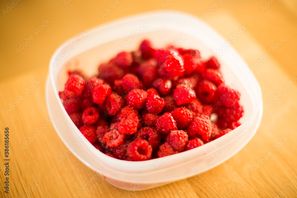 Close up of raspberries in a plastic Tupperware container Close up of raspberries in a plastic Tupperware container