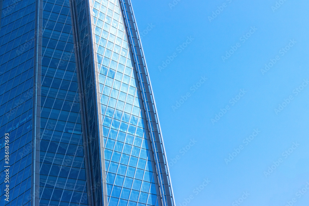 sky and exterior glass walls of a modern Corporate building. Business offices of skyscraper on blue sky background.