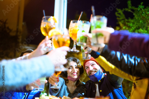 Friends drinking spritz and mojito in a cocktail bar with face masks photo