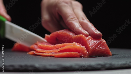Fotografie Sushi Chef Slices fresh Salmon on the sushi bar