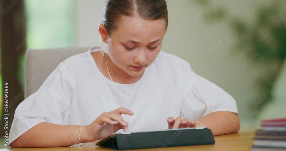 Closeup focused teen girl at the desk, is writing on tablet. First plan and backgroung are blurred Closeup focused teen girl at the desk, is writing on tablet. First plan and backgroung are blurred