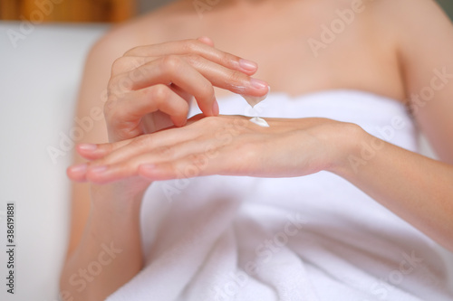 Woman applying cream lotion on hand with wood background  Beauty concept.