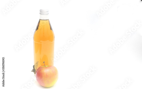 One whole apple with leaf and a bottle of apple cider vinegar on white background, copyspace.