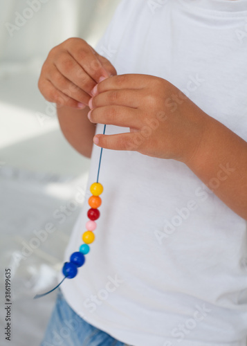 The boy makes a bead decoration. Mix the colored beads. Hobby concept. Accessory, design. 