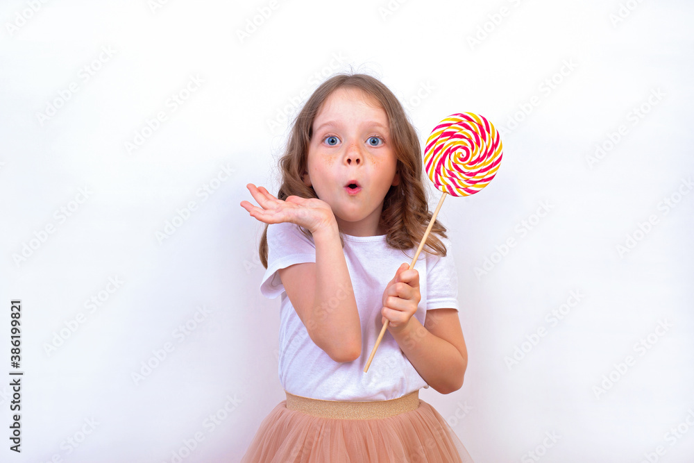 Surprised cute girl with a large multi-colored Lollipop in her hand.