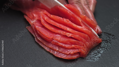 Chef takes out bones from the salmon fillet, cutting fish on slices for cooking sushi in 4k resolution in slow motion