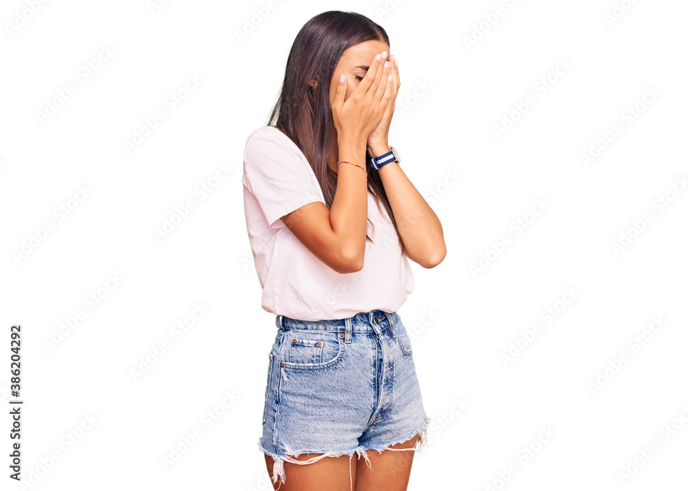 Young hispanic woman wearing casual white tshirt with sad expression covering face with hands while crying. depression concept. Young hispanic woman wearing casual white tshirt with sad expression covering face with hands while crying. depression concept.