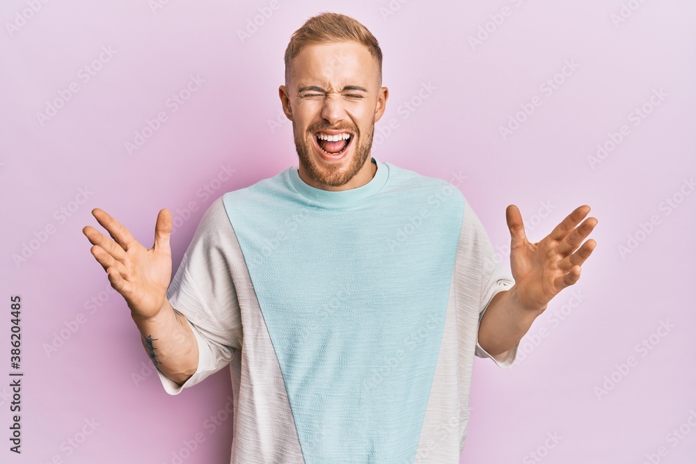 Young caucasian man wearing casual clothes celebrating mad and crazy for success with arms raised and closed eyes screaming excited. winner concept Young caucasian man wearing casual clothes celebrating mad and crazy for success with arms raised and closed eyes screaming excited. winner concept