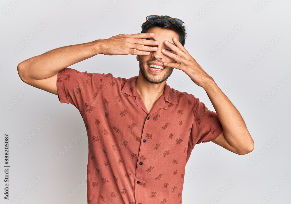 Young handsome man wearing casual summer clothes covering eyes with hands smiling cheerful and funny. blind concept. Young handsome man wearing casual summer clothes covering eyes with hands smiling cheerful and funny. blind concept.