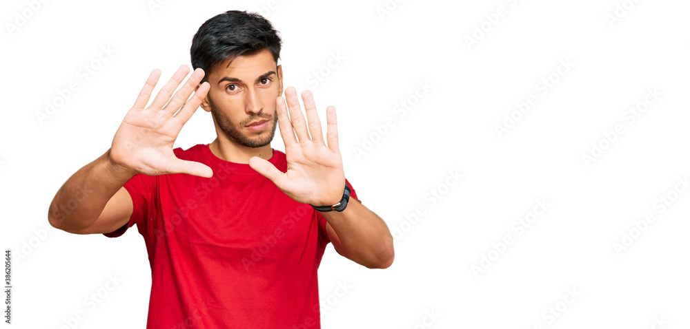Young handsome man wearing casual red tshirt doing frame using hands palms and fingers, camera perspective Young handsome man wearing casual red tshirt doing frame using hands palms and fingers, camera perspective