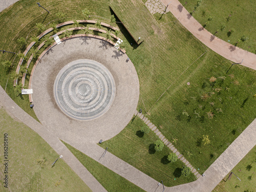 Summer park with green lawns, fountain and paths, aerial drone top view