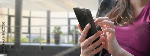 Bild auf Leinwand Young woman or teenager texting , chaten and type, using mobile phone smartphone in a modern school or business office building