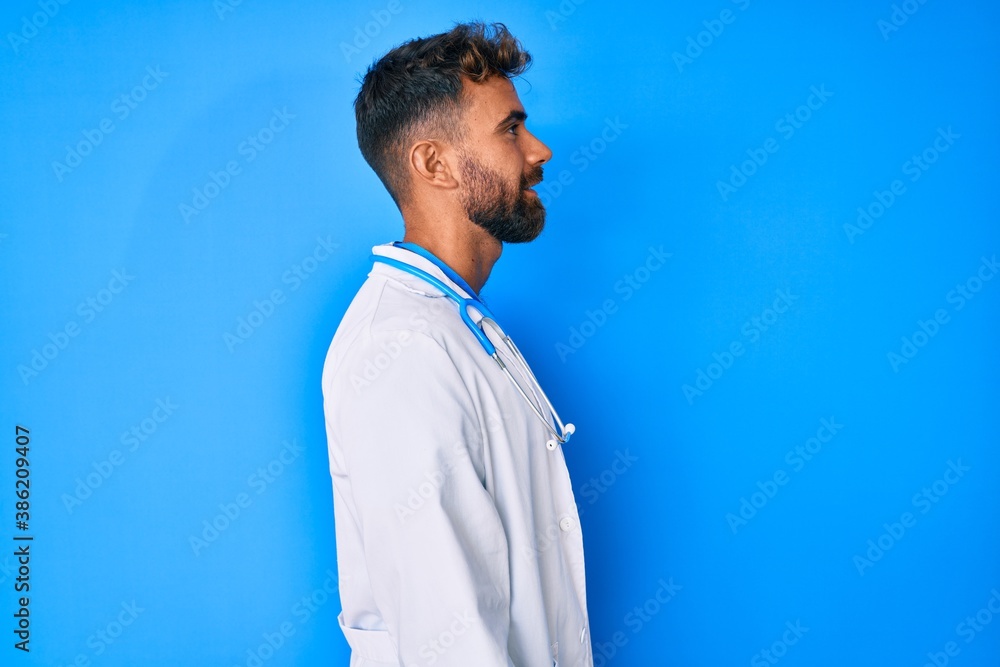 Young hispanic man wearing doctor uniform and stethoscope looking to side, relax profile pose with natural face with confident smile. Young hispanic man wearing doctor uniform and stethoscope looking to side, relax profile pose with natural face with confident smile.