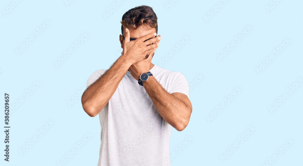 Fototapeta premium Young hispanic man wearing casual clothes and glasses covering eyes and mouth with hands, surprised and shocked. hiding emotion