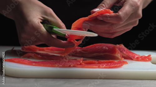 male chef cuts fillet of fresh salmon into large chunks. Cooking fish in kitchen. Preparation of ingredients by chef to prepare dish. Cooking in the restaurant kitchen. Food ingredients for gourmets