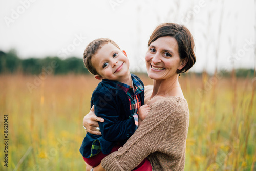 Portrait of mother holding young happy boy outdoors photo