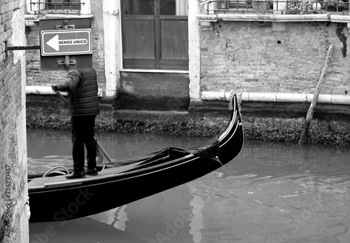 Venice, Italy, December 28, 2018 evocative black and white image of a typical Venice canal with signposts for boats gondolas and a moving gondola