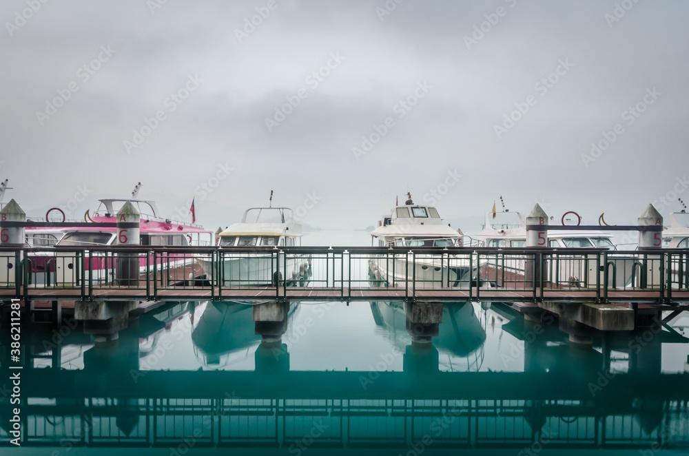 Fototapeta premium Boat at pier in misty sun rise at Sun Moon lake, Taiwan