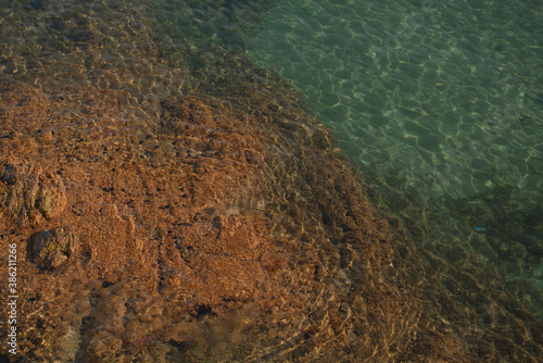turquoise Mediterranean sea detail during summer with rocks, waves, and sunlight horizontal