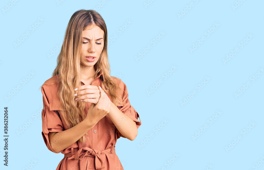 Beautiful caucasian woman with blonde hair wearing summer jumpsuit suffering pain on hands and fingers, arthritis inflammation Beautiful caucasian woman with blonde hair wearing summer jumpsuit suffering pain on hands and fingers, arthritis inflammation