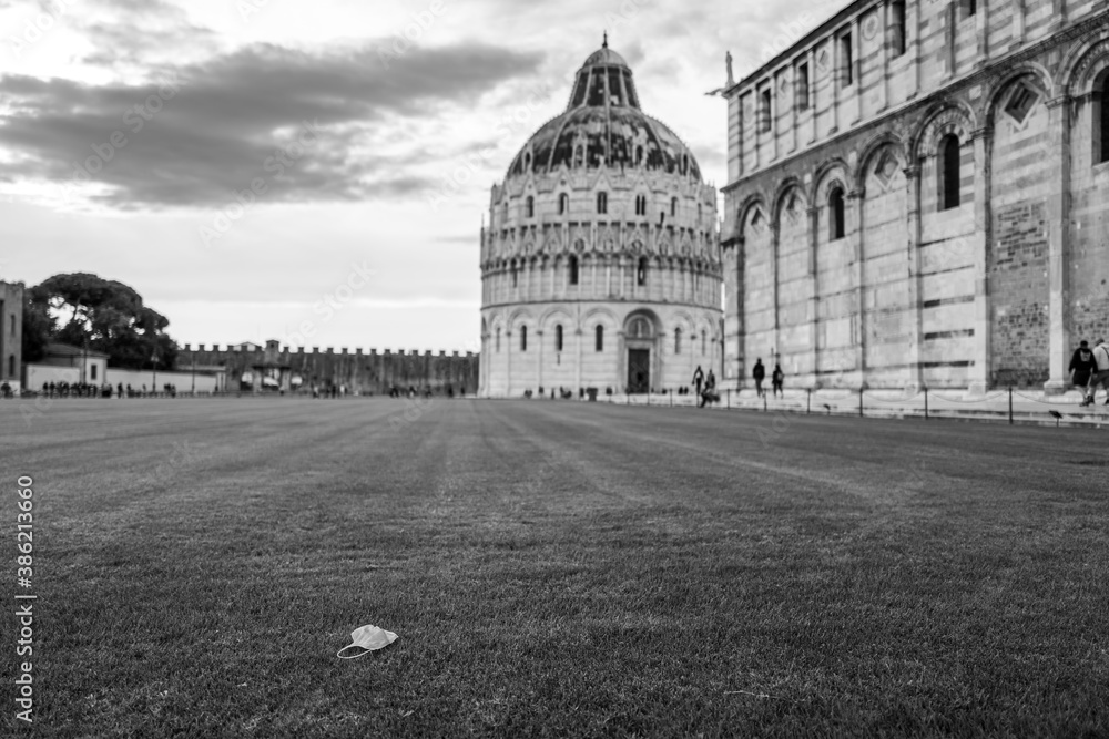 A Corona mask in front of the cathedral and baptistery in Pisa