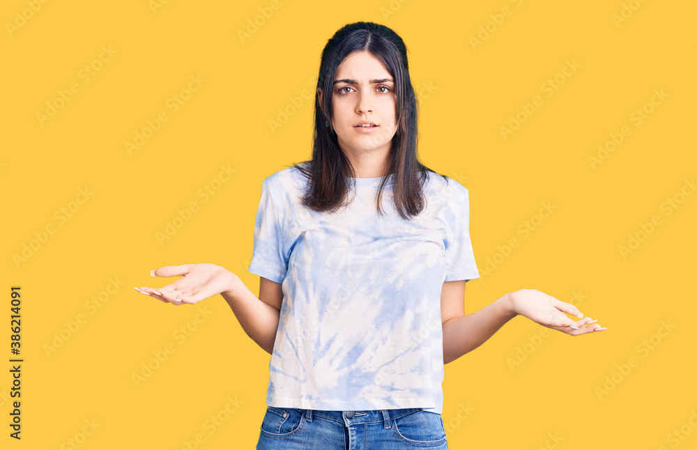 Young beautiful girl wearing casual t shirt clueless and confused with open arms, no idea concept. Young beautiful girl wearing casual t shirt clueless and confused with open arms, no idea concept.