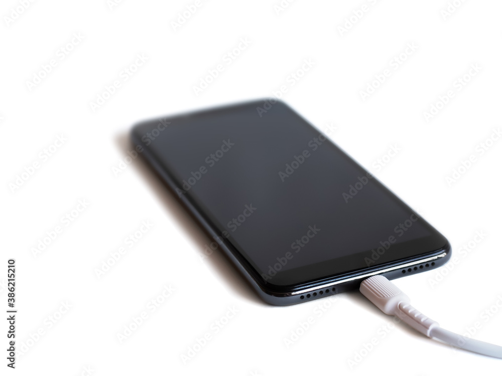black smartphone with connected cable for charging the battery on white background black smartphone with connected cable for charging the battery on white background