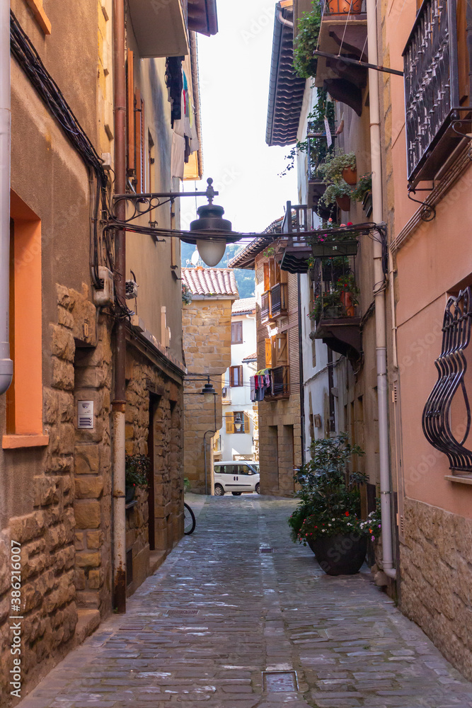 Fototapeta premium Narrow street in old town, Europe. Downtown in mountains, Spain. Facade of ancient houses. Historical cityscape. Empty town. Quarantine pause in Spain. Residential district with no people. Old centre.