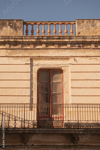 old building detail of a balcony with red doors and sunlight in the small coastal village: Cadaques, Girona, Spain