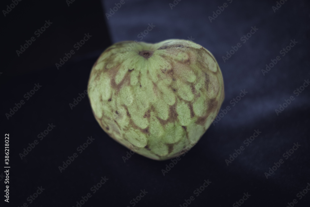 Obraz premium Cherimoya on black background. Annona cherimola. Seasonal fruit. Heart shape fruit.