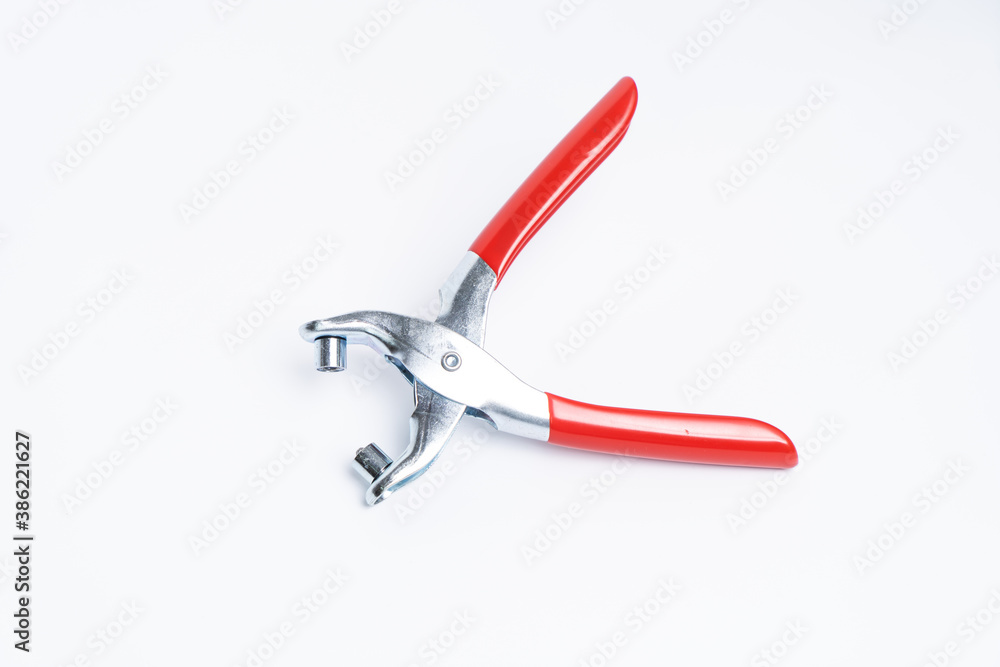 Red rivet puncher, riveting pliers close-up on a white background. Puncher and grommet installer. Tool for installing the eyelet. Isolated object Red rivet puncher, riveting pliers close-up on a white background. Puncher and grommet installer. Tool for installing the eyelet. Isolated object