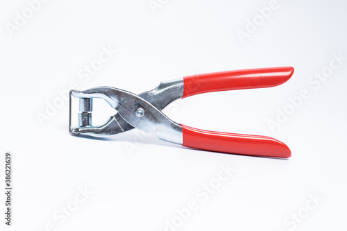 Red rivet puncher, riveting pliers close-up on a white background. Puncher and grommet installer. Tool for installing the eyelet. Isolated object