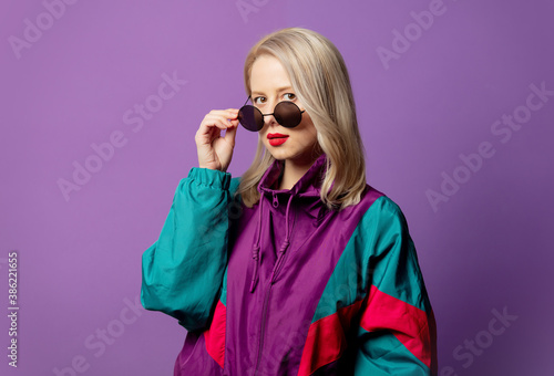 Style blonde in 80s windbreaker and roud sunglasses on purple background photo