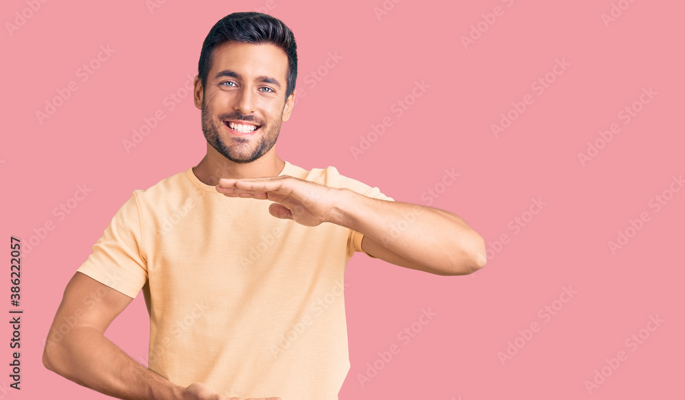 Young hispanic man wearing casual clothes gesturing with hands showing big and large size sign, measure symbol. smiling looking at the camera. measuring concept. Young hispanic man wearing casual clothes gesturing with hands showing big and large size sign, measure symbol. smiling looking at the camera. measuring concept.