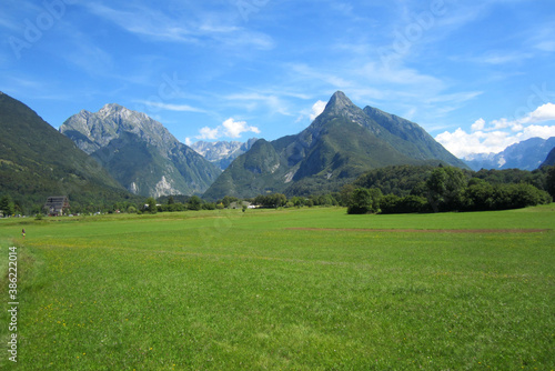 Panorama of the Julian Alps. Mountains and green meadow on a sunny summer day