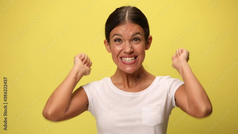 young casual woman looking down, laughing, feeling excited, dancing around and celebrating the victory on yellow background young casual woman looking down, laughing, feeling excited, dancing around and celebrating the victory on yellow background