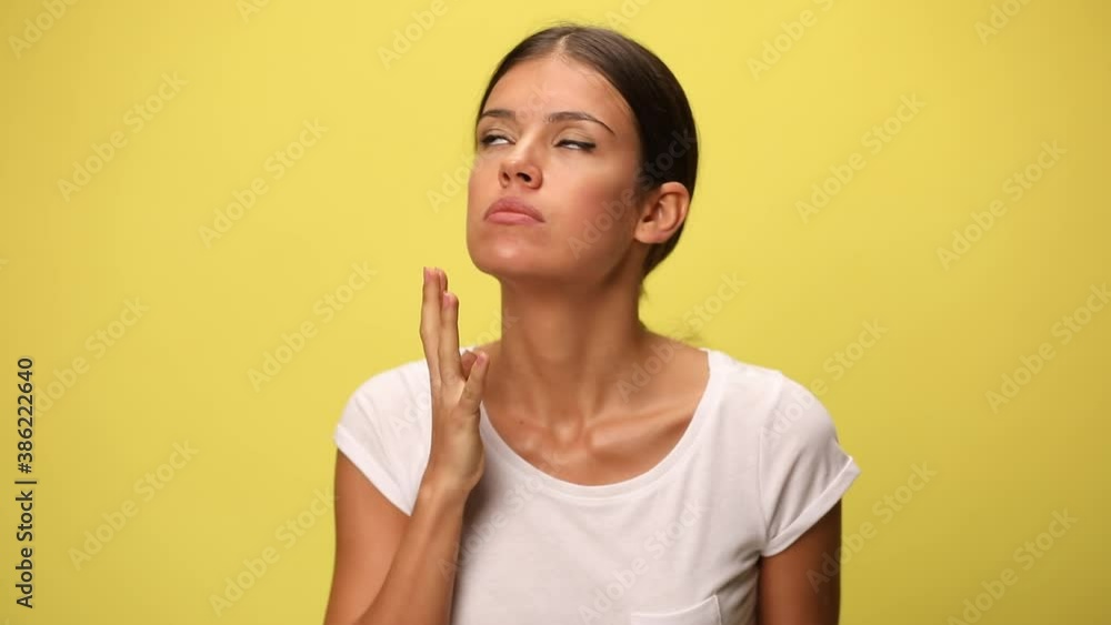beautiful casual woman nagging someone, pointing her finger, showing her fist and being desperate and angry on yellow background beautiful casual woman nagging someone, pointing her finger, showing her fist and being desperate and angry on yellow background