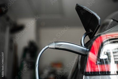 Electric Vehicle Charging Cable Plugged In with Garage Background