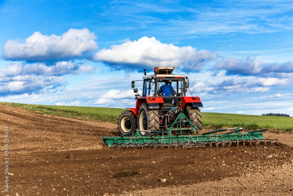 Agriculture red tractor cultivating field over blue sky. Old red tractor in the agricultural field; mechanism. Tractor plowing land. Harvester sowing wheat. Agriculture red tractor cultivating field over blue sky. Old red tractor in the agricultural field; mechanism. Tractor plowing land. Harvester sowing wheat.