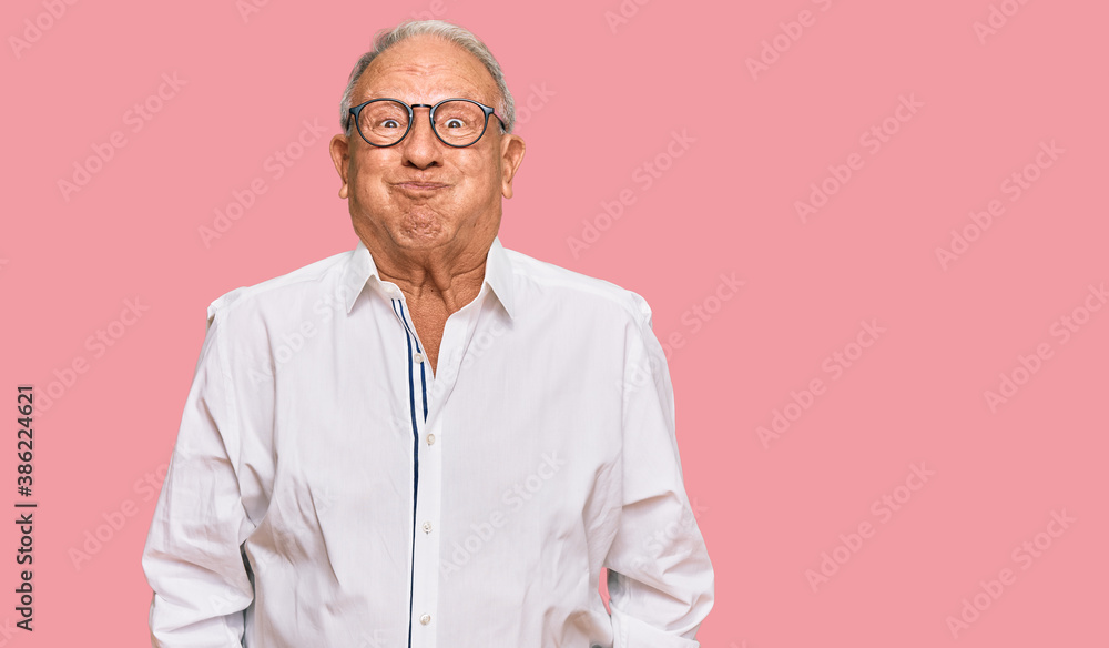 Senior caucasian man wearing business shirt and glasses puffing cheeks with funny face. mouth inflated with air, crazy expression. Senior caucasian man wearing business shirt and glasses puffing cheeks with funny face. mouth inflated with air, crazy expression.