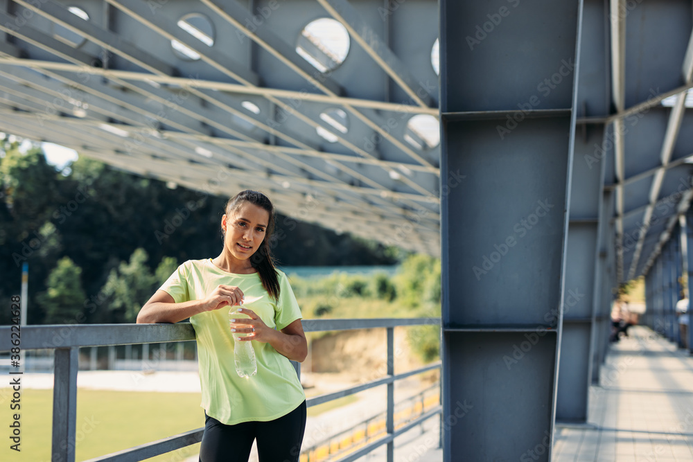 Smiling woman in activewear posing on camera at stadium Smiling woman in activewear posing on camera at stadium